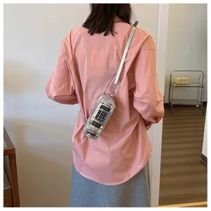 Creative silver brick phone shaped crossbody bag worn by a model in a pink shirt