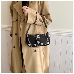Close-up of black baguette bag with pearl heart accents and silver chain on a model