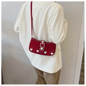 Detail of red baguette shoulder bag with pearl heart decorations and silver metal buckle