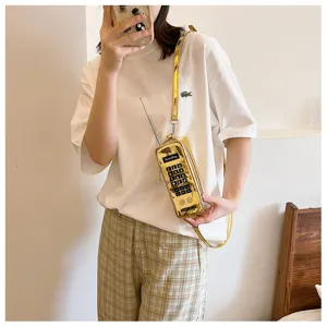Close-up detail shot of creative vintage mobile phone shaped crossbody bag in metallic gold finish