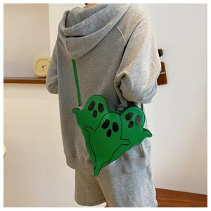 Whimsical green triple ghost-shaped crossbody bag for women shown worn on a grey hoodie