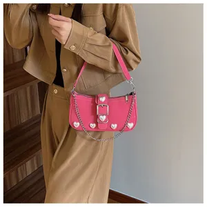 Detailed view of a stylish pink baguette bag with heart pearl decorations worn by a model