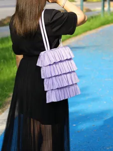 Lavendelfarbene Falten-Tasche mit Rüschen im Cake-Skirt-Design im Freien getragen