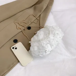 Détail du sac de soirée blanc avec roses 3D et élégante poignée en perles nacre