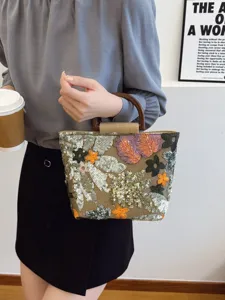 Elegante borsa in lino con ricamo floreale di paillettes e manico in legno.