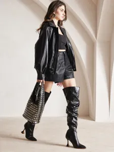 Punk style black bucket bag with silver stud embellishments worn by a fashion model
