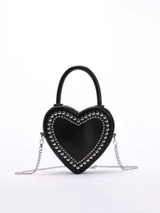 Detailed view of the black heart-shaped crossbody bag featuring silver stud embellishments.