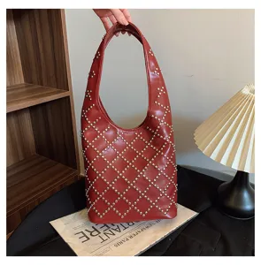 Close-up of a punk-style burgundy bucket bag with diamond-patterned silver rivets.