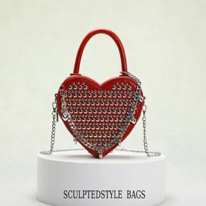 Red heart-shaped crossbody bag for women with double-sided metal rivets and chain tassel decor.