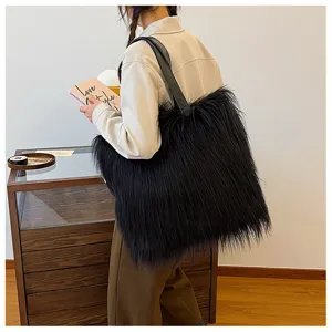 Large black faux fur tote bag carried as a shoulder bag in a stylish interior setting