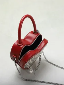Red heart-shaped handbag detail showcasing stylish silver chain and rivet decoration.