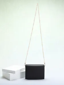 Detailopname van een zwarte minimalistische crossbodytas met gouden ketting