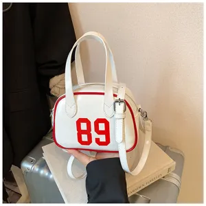 Detail of white bowling handbag with red number 89 and contrast piping