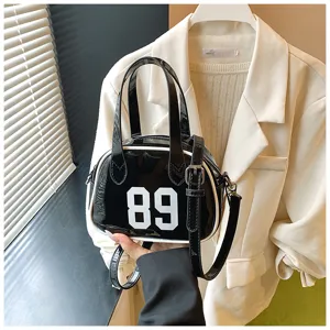 Close-up view of a stylish black patent leather bowling bag featuring a white 89 print detail