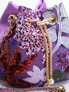 Detailed macro view of vibrant floral embroidery and shimmering sequins on a purple mesh bucket bag