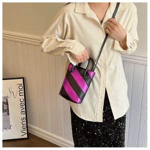Small purple and black striped PU bucket bag with crossbody strap shown on model