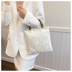 Elegant white embroidered butterfly evening handbag featuring natural bamboo top handles