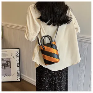 Detailed view of the stylish striped bucket bag worn crossbody by a model in a room.