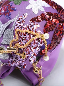Close-up of purple sequined floral embroidery bucket bag with gold chain and pearl charms