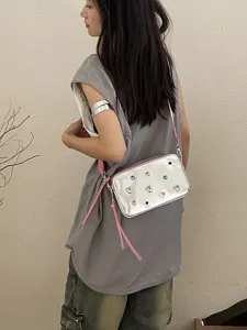 Bolso de cámara plateado estilo dopamina con pedrería de colores y correa rosa ajustable.