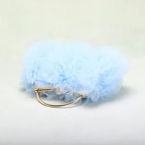 Dettaglio elegante della borsa da sera in tulle celeste con manico dorato e chiusura in strass