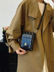 Gothic black skull crossbody bag with silver eyelets and rivets shown on a trench coat