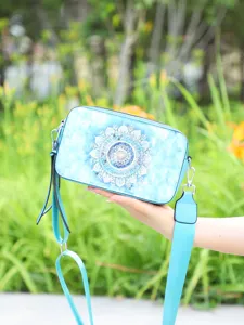 Detailed view of light blue camera bag with mandala print in natural outdoor light