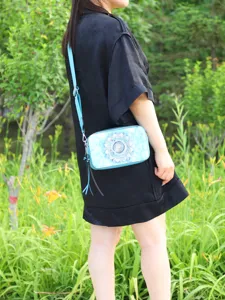 Outdoor lifestyle shot of a woman wearing a blue mandala print camera bag crossbody.