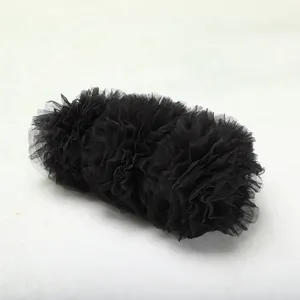 Dettaglio degli strati di tulle nero arricciato su una borsa da sera.