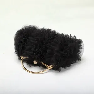 Dettaglio della borsa da sera in tulle nero plissettato con manico circolare dorato.