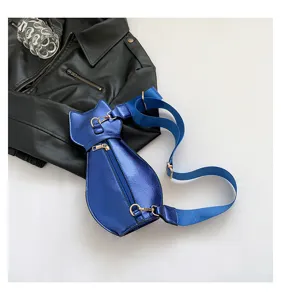 Close-up of blue metallic cat-shaped crossbody chest bag on black leather jacket