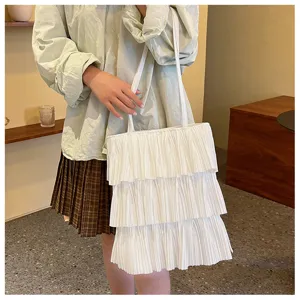 Elegante weiße plissierte Rüschen-Tragetasche im Stufenrock-Stil, Modellfoto.