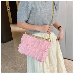 Rosa gesteppte Jeans-Umhängetasche mit goldener Kette und Fransen, elegant von Model präsentiert.