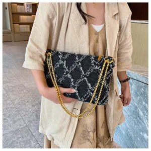 Detailansicht der stylischen Jeans gesteppten Schultertasche mit goldener Kette.