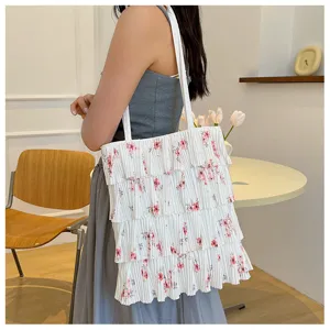 Detailansicht einer geblümten, plissierten Tasche, die von einem Model getragen wird