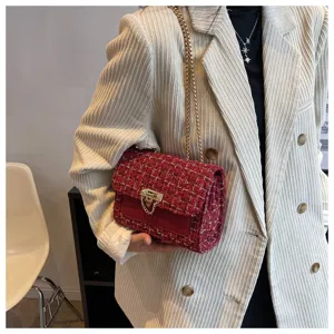 Detail of a red tweed crossbody bag with gold chain strap on a white blazer.