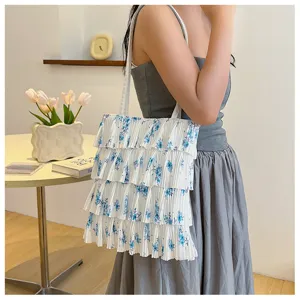 Modell trägt eine weiß plissierte Blumentasche mit einem mehrlagigen Rüschendesign.