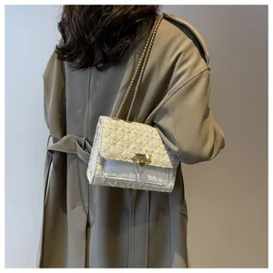 Elegant cream tweed crossbody bag with gold chain strap shown on model outdoors.