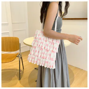 Model trägt eine weiße Plissee-Tasche mit rosa Punkten und gestuftem Rüschendesign