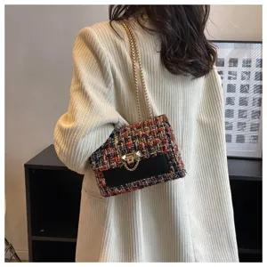 Elegant multicolor tweed small square bag with gold chain strap carried by a model