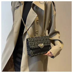Detail shot of a black tweed chain bag worn with a stylish khaki trench coat