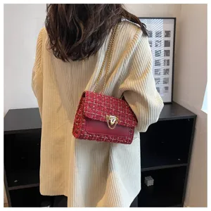 Close-up detail of a red tweed and leather shoulder bag with gold chain strap on model
