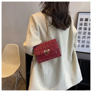 Close-up detail of red tweed chain bag worn on shoulder over beige blazer