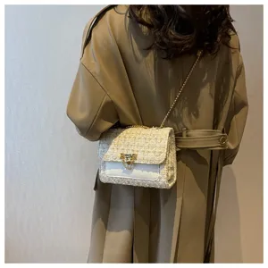 Rear view of a model carrying a beige tweed chain flap bag on a khaki trench coat