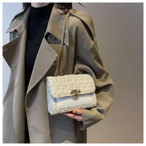 Close-up detail of white tweed chain bag with elegant gold hardware on trench coat