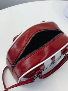 Red and white oiled leather bowler handbag with spacious interior and zipper closure.