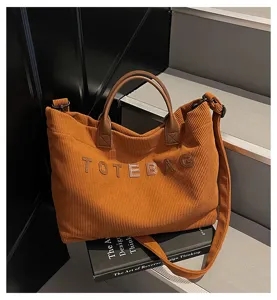 Detailed view of casual brown corduroy tote bag with embroidered letters and shoulder strap.