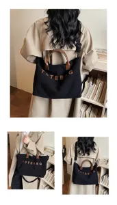 Detailed view of the black corduroy tote bag with brown handles and letter patches.