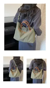 Detail view of the green corduroy tote bag showing embroidered text and brown leather handles.