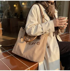 Detail shot of corduroy tote bag in khaki with brown handles, outdoor lifestyle scene.
